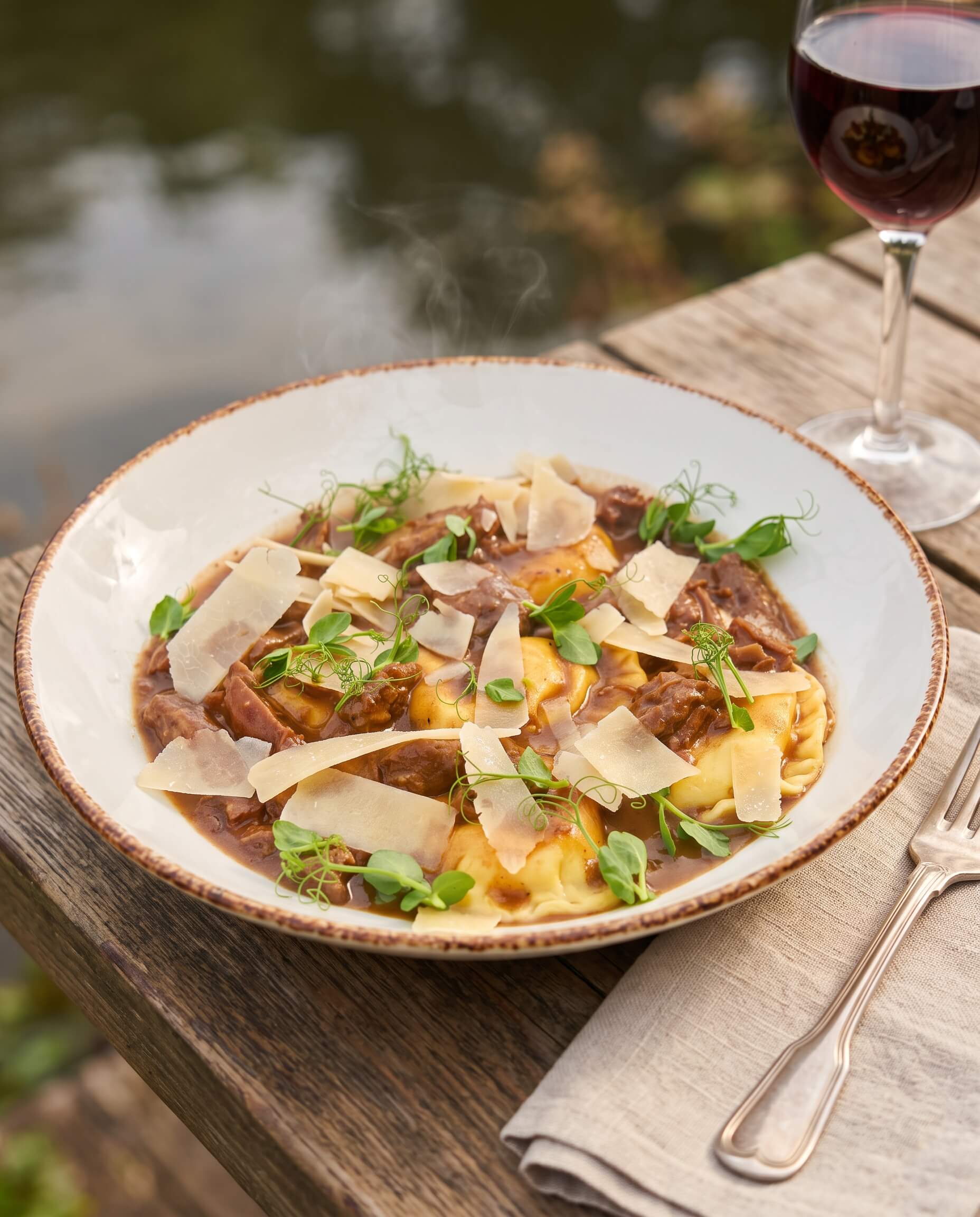 Sweet potato ravioli with shredded pork tenderloin, shaved Parmesan, and greens